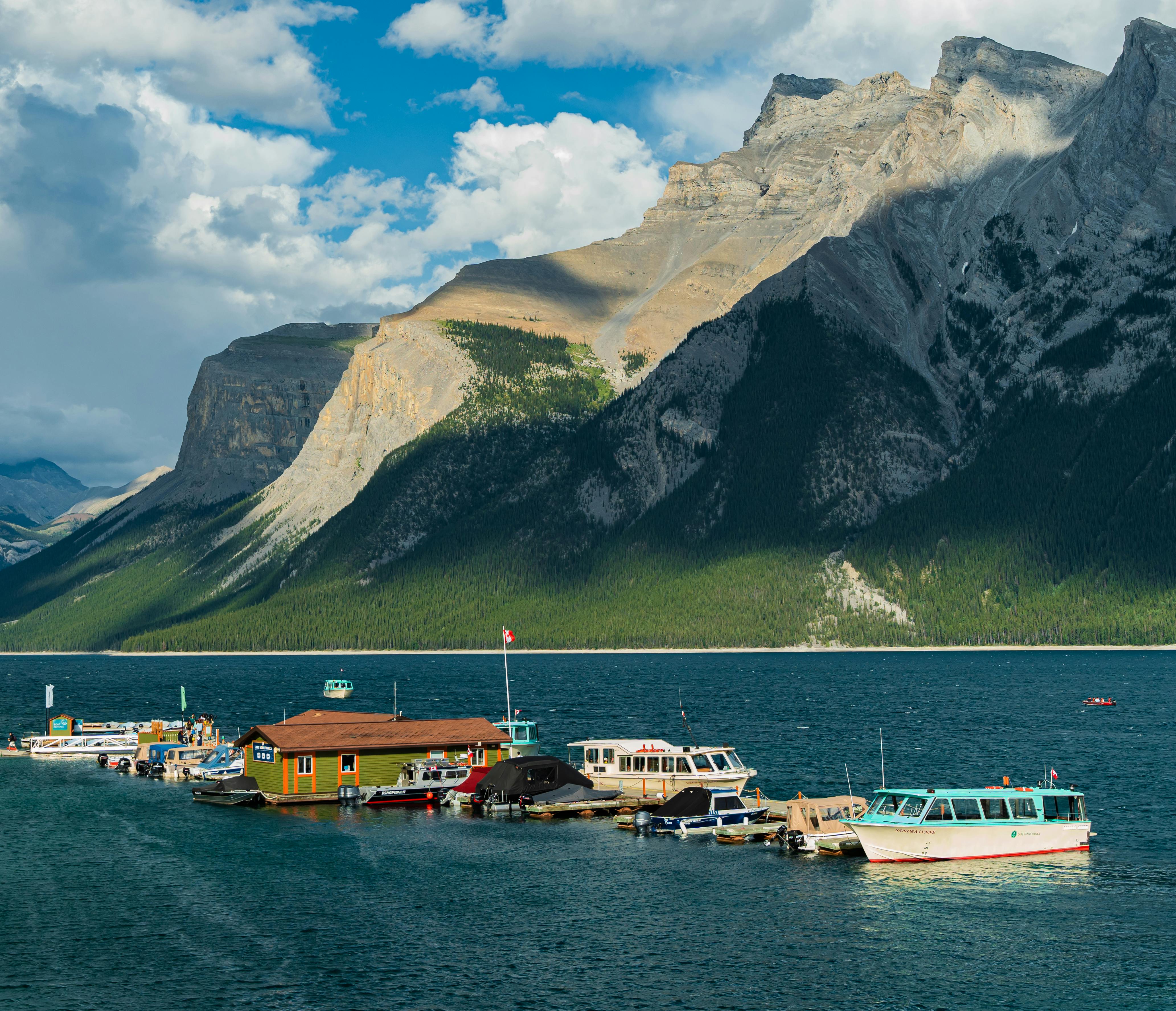 Beautiful landscape of boats moored on a lake with majestic mountains in the background.