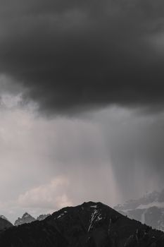 A dark and moody mountain landscape with storm clouds looming overhead, showcasing nature's raw power.