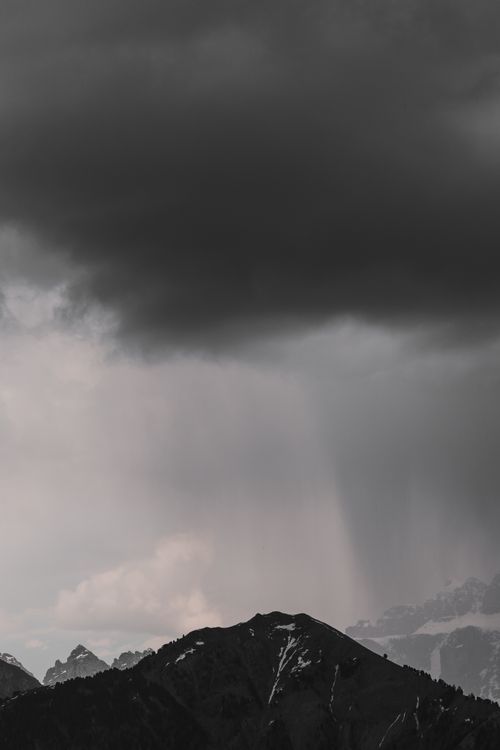 Free A dark and moody mountain landscape with storm clouds looming overhead, showcasing nature's raw power. Stock Photo