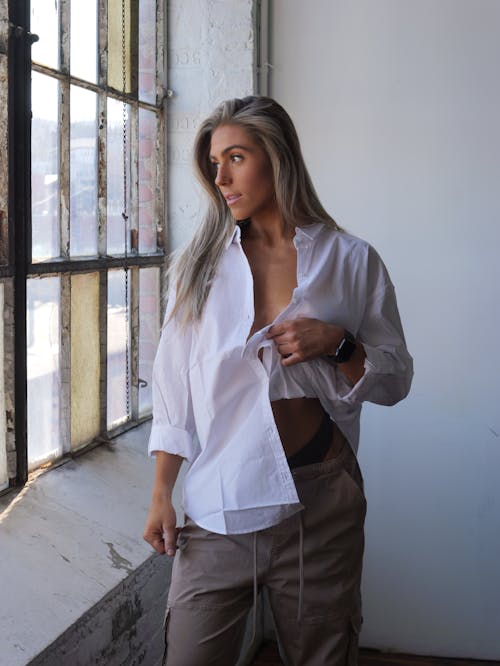 Model in a White Blouse and Beige Pants Posing in an Old Factory