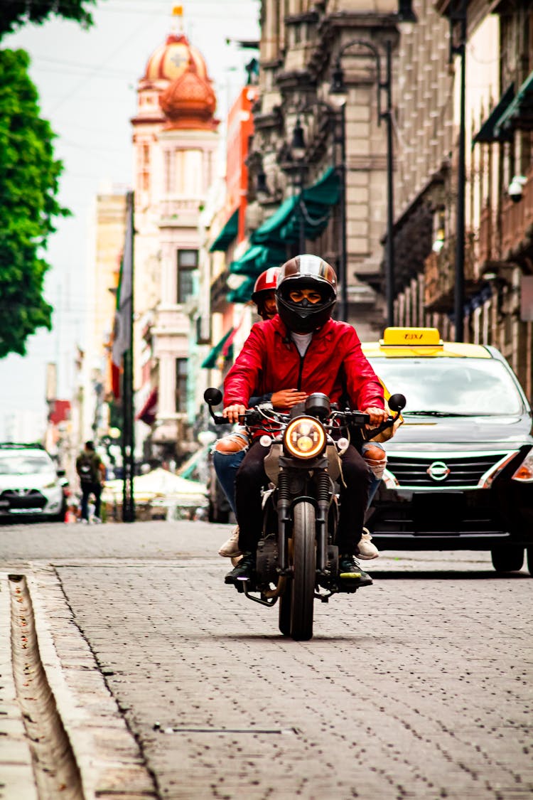 A Man Riding A Motorcycle Down A City Street