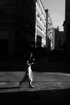 Silhouette of a woman walking in a city street, showcasing urban architecture and dynamic lighting.