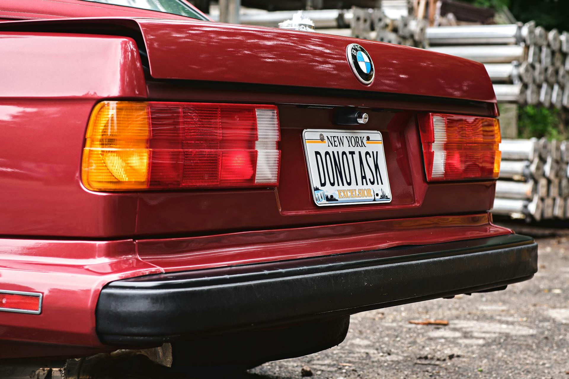 Rear view of a vintage red BMW E30 featuring a unique New York license plate.