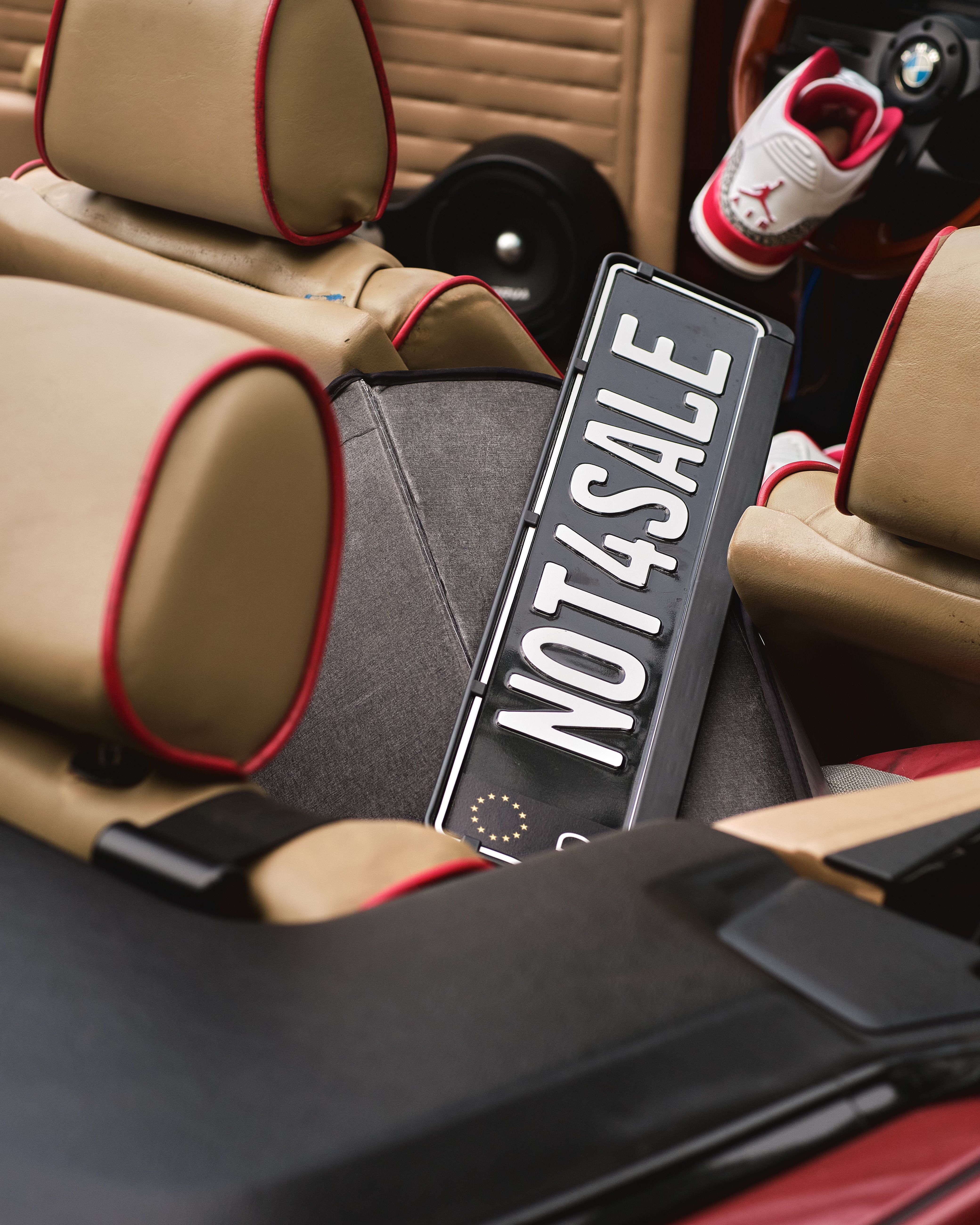 Stylish car interior featuring a NOT4SALE license plate and Air Jordan sneakers.