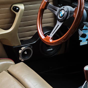 Close-up of a vintage BMW E30 interior showcasing a wooden steering wheel and leather upholstery for an automotive classic feel.