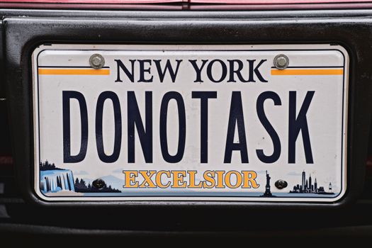 Detailed close-up of a custom New York license plate with unique lettering 'DONOTASK'.