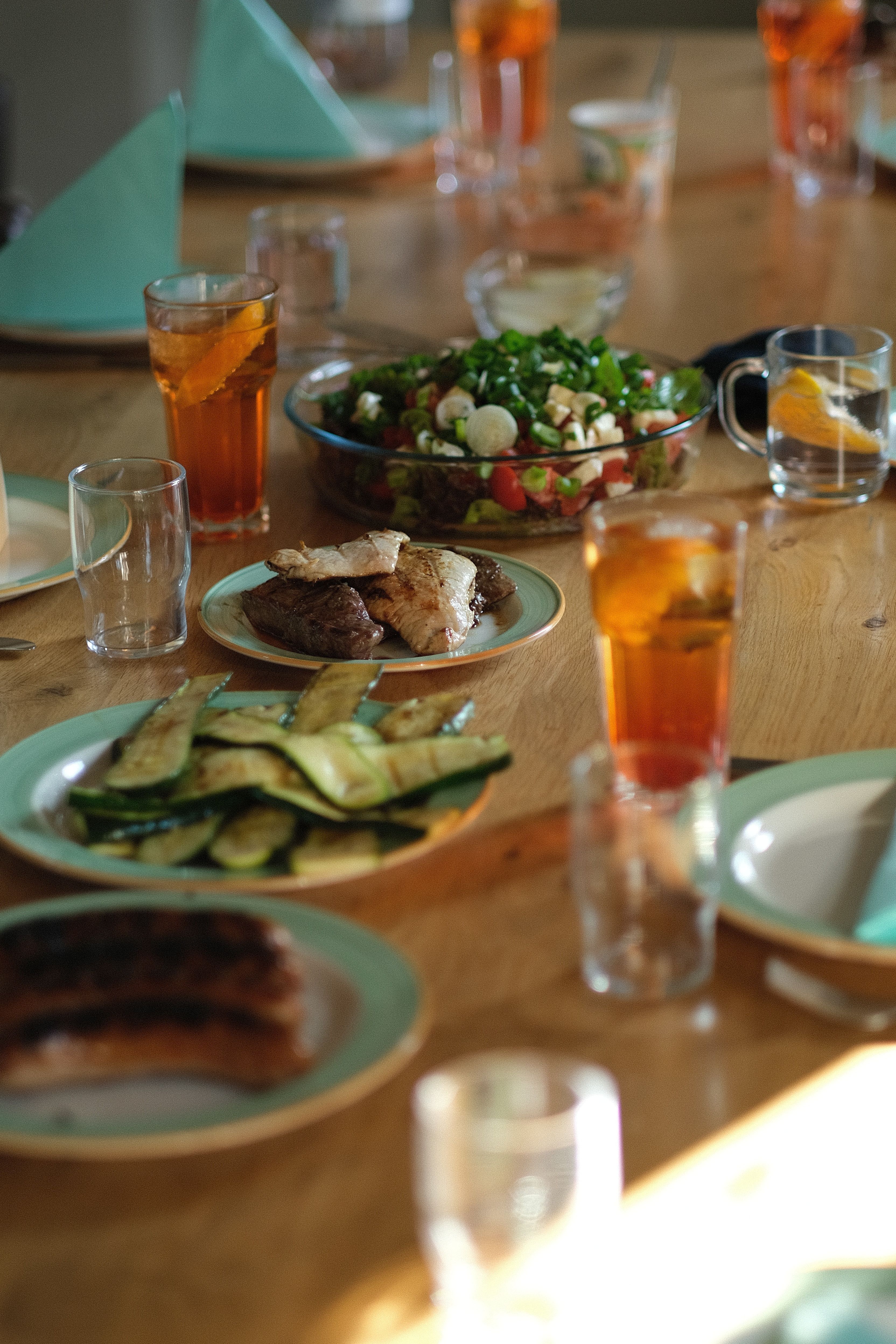 A cozy dinner setting with salad, grilled meat, drinks, and tableware. Perfect for family gatherings.