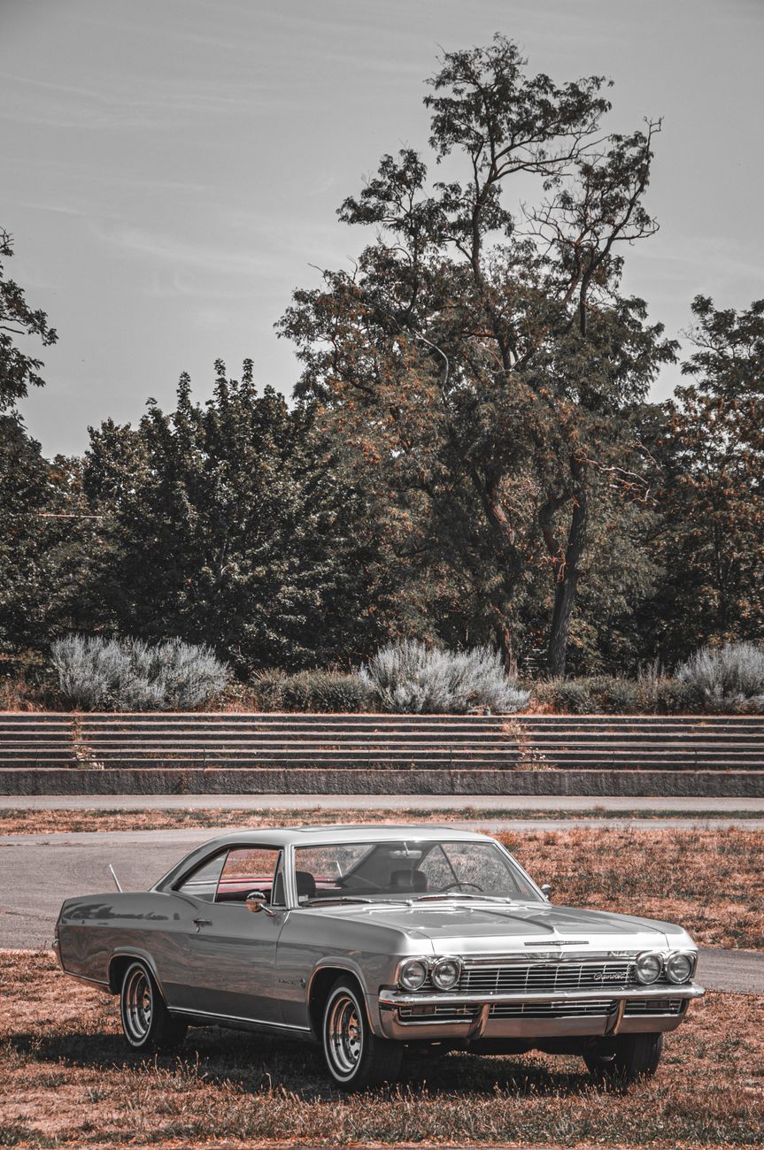 A classic Chevrolet Impala parked in a rural outdoor setting, capturing the essence of vintage automotive style.