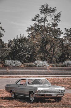 A classic Chevrolet Impala parked in a rural outdoor setting, capturing the essence of vintage automotive style.