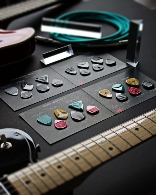 Free A variety of colorful guitar picks and accessories displayed on a showcase with a guitar neck visible. Stock Photo