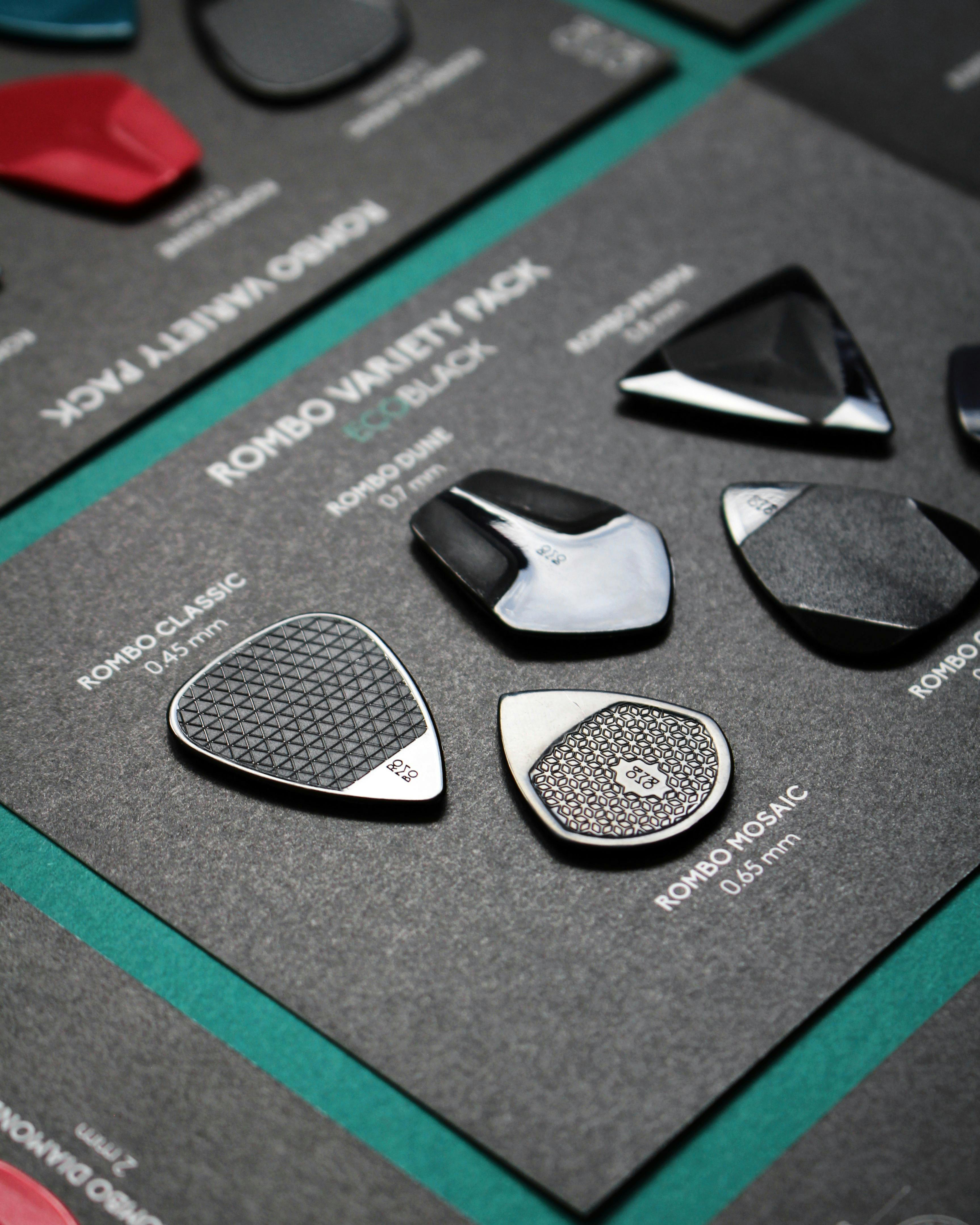 Close-up of various guitar picks arranged on a black matte display background.