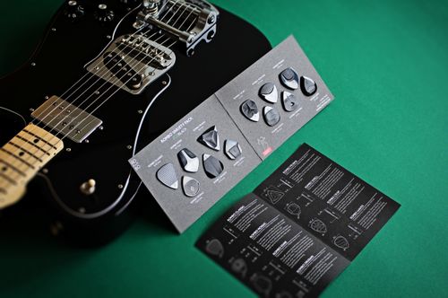 Free Black electric guitar with set of guitar picks and instructions on a green surface. Stock Photo