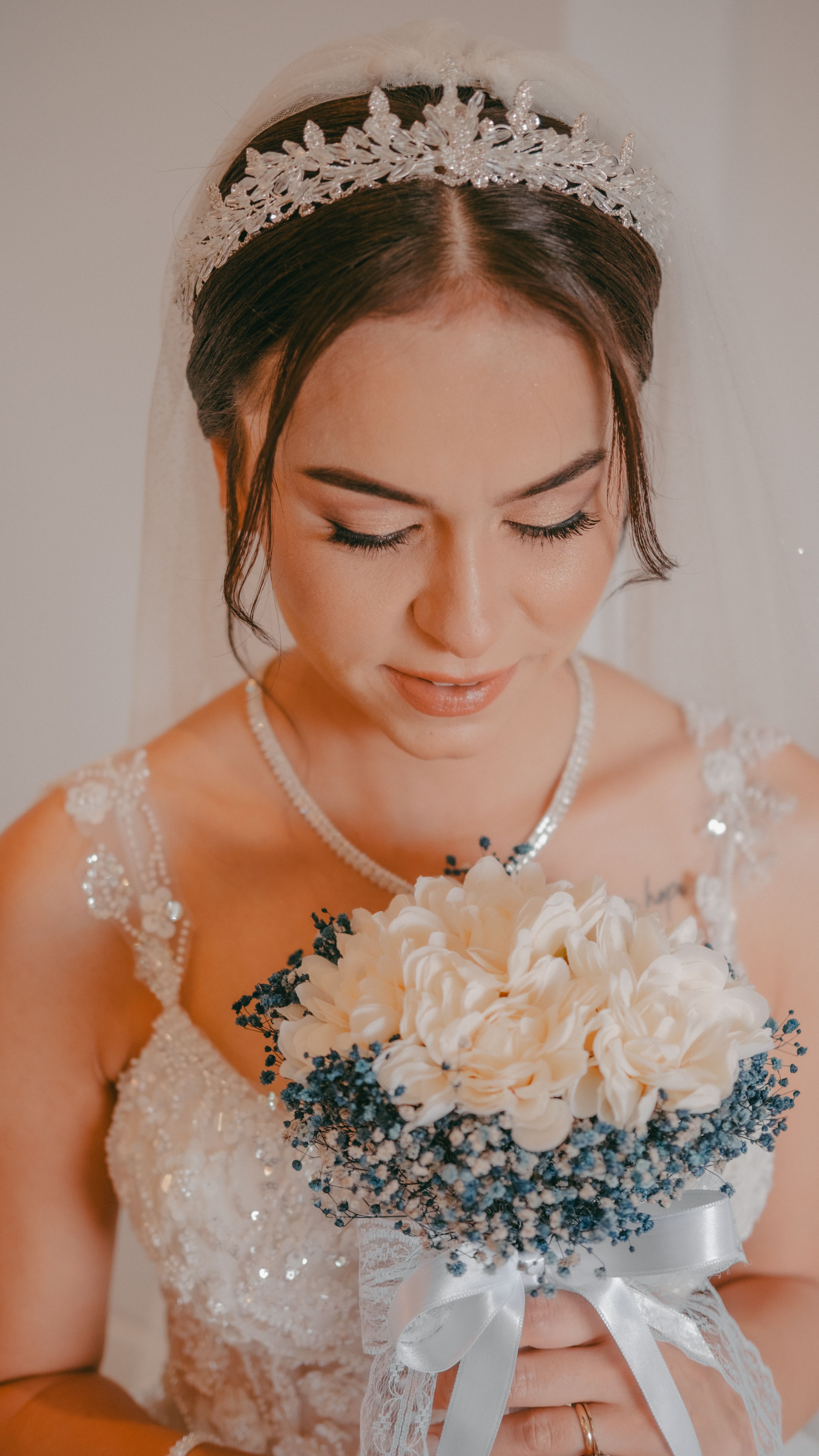 A beautiful bride holding a delicate bouquet while looking down. Perfect for wedding themes.