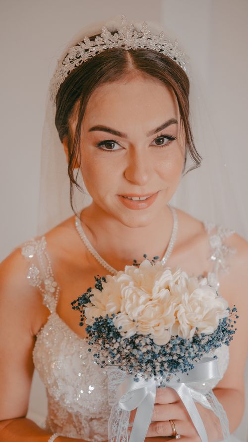 Free Bride in a stunning wedding gown holding a delicate bouquet with blue and white flowers. Stock Photo