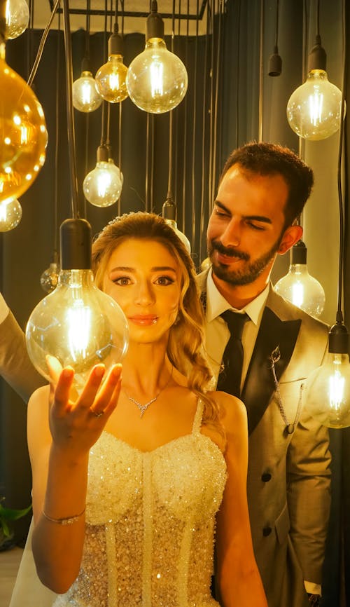 Newlyweds Standing among Light Bulbs