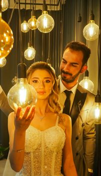 Bride and groom in a romantic setting surrounded by glowing bulbs exemplifying elegant wedding photography.
