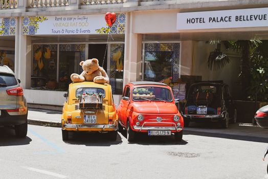 Vintage Fiat cars with a teddy bear decoration and balloon in Opatija, Croatia's urban streets.