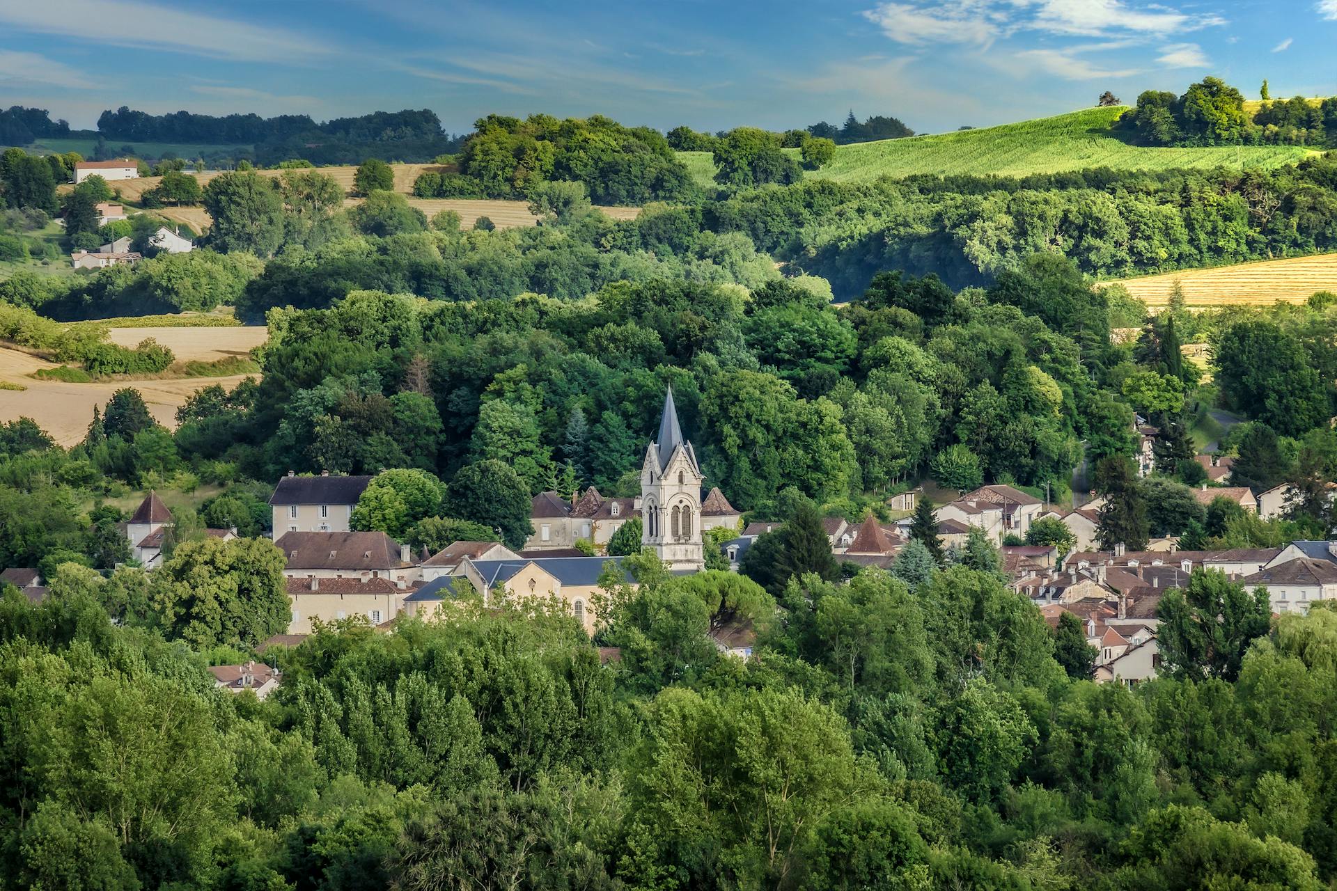 Aerial view of Tocane-Saint-Apre village nestled among lush greenery and rolling hills in Nouvelle-Aquitaine, France.