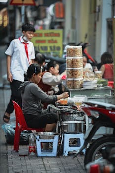 Local vendor preparing street food in bustling Nha Trang market, Vietnam.