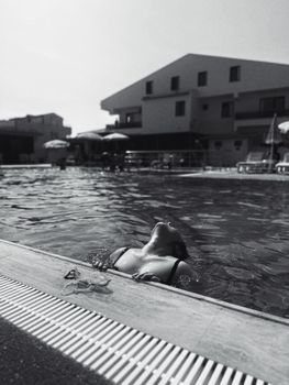 A woman enjoying relaxation in a swimming pool, captured in black and white for a serene effect.