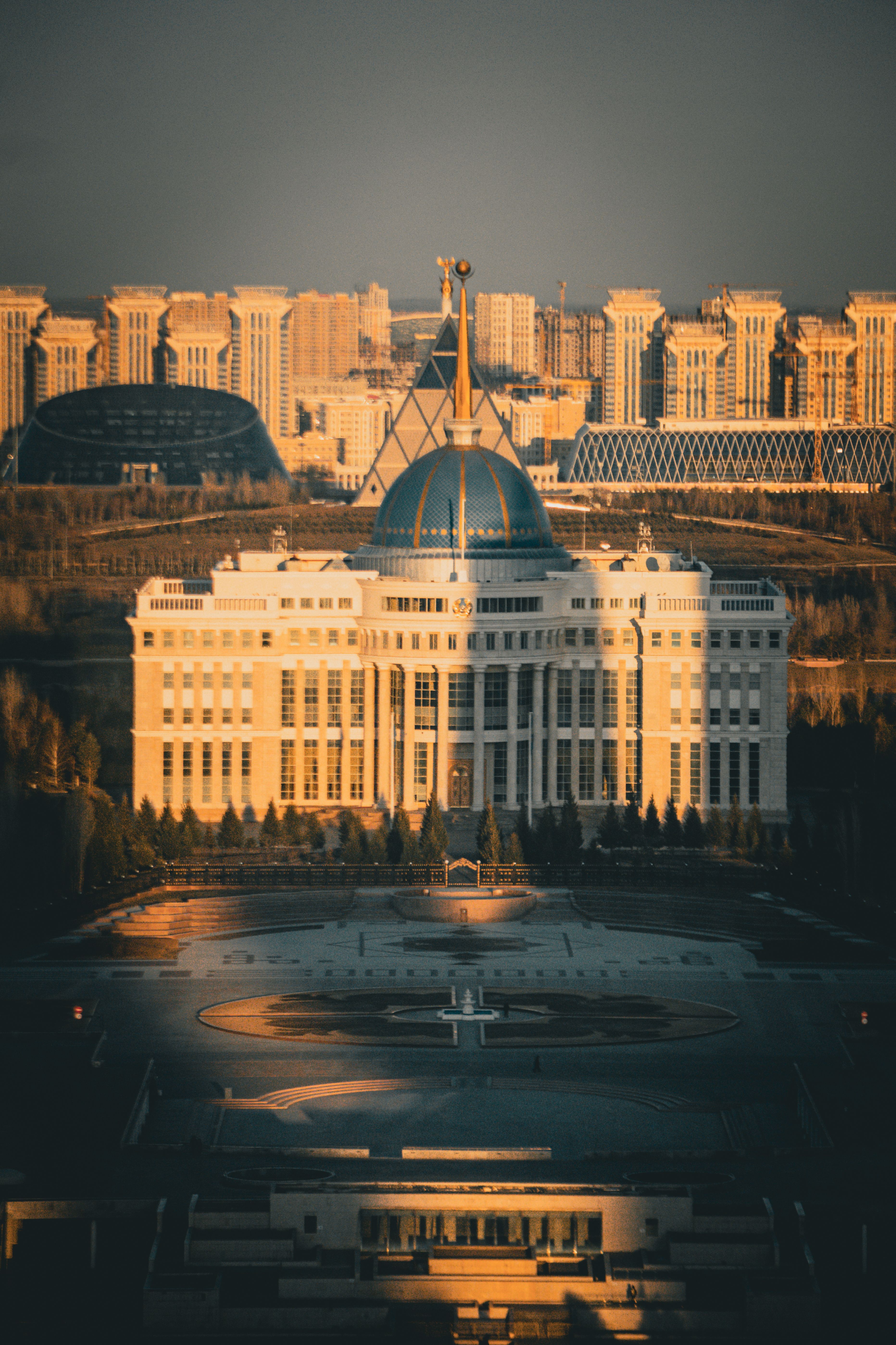 A stunning drone view of Ak Orda Presidential Palace in Astana, Kazakhstan, illuminated by sunset light.