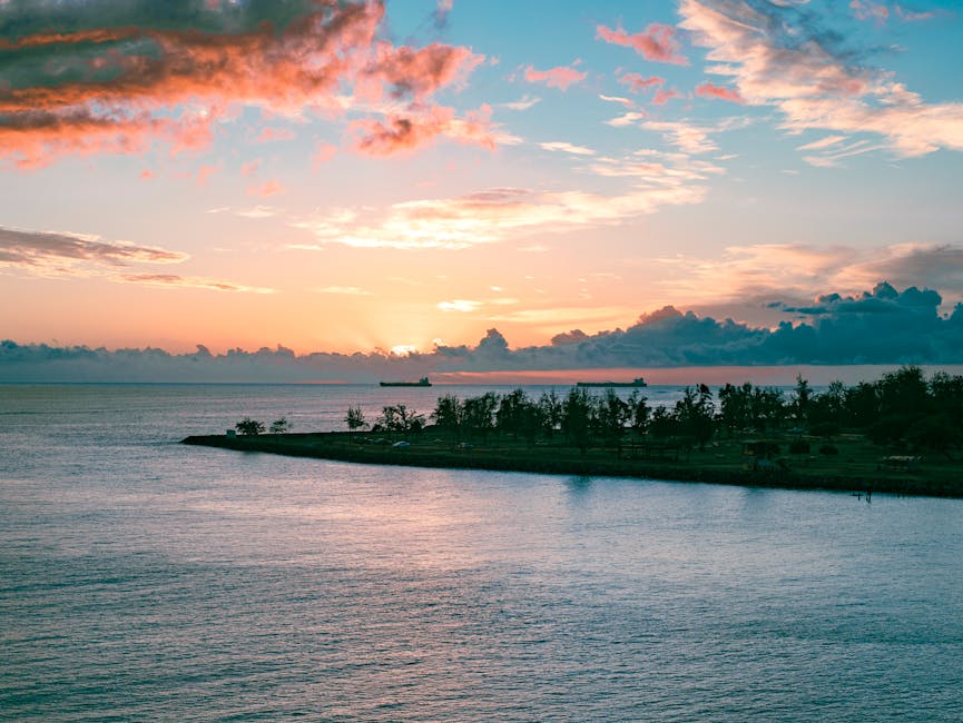 A tranquil ocean sunset over Honolulu with silhouettes of ships and clouds.