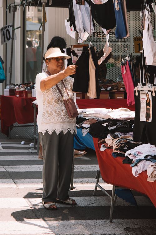Free Elderly woman shopping for clothes at an outdoor market in Valencia, Spain. Stock Photo