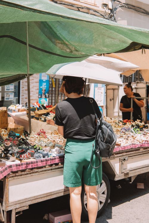 Free Woman browsing shoe stall at bustling Valencia street market in Spain, sunny day Stock Photo