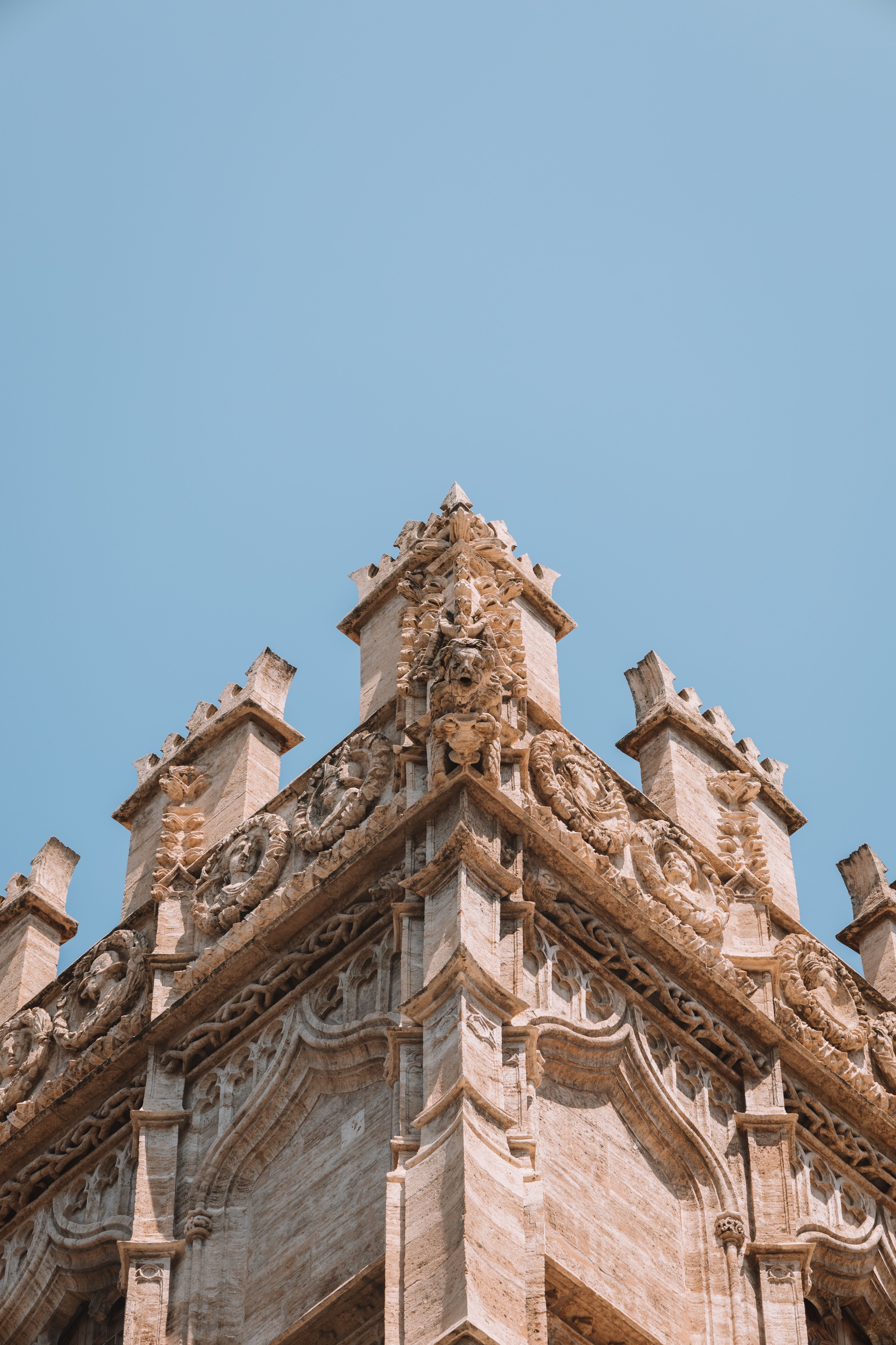 Intricate details of the Llotja de la Seda's Gothic architecture captured under clear blue skies in Valencia, Spain.