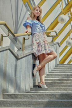 Young woman in fashionable outfit posing confidently on modern urban staircase.