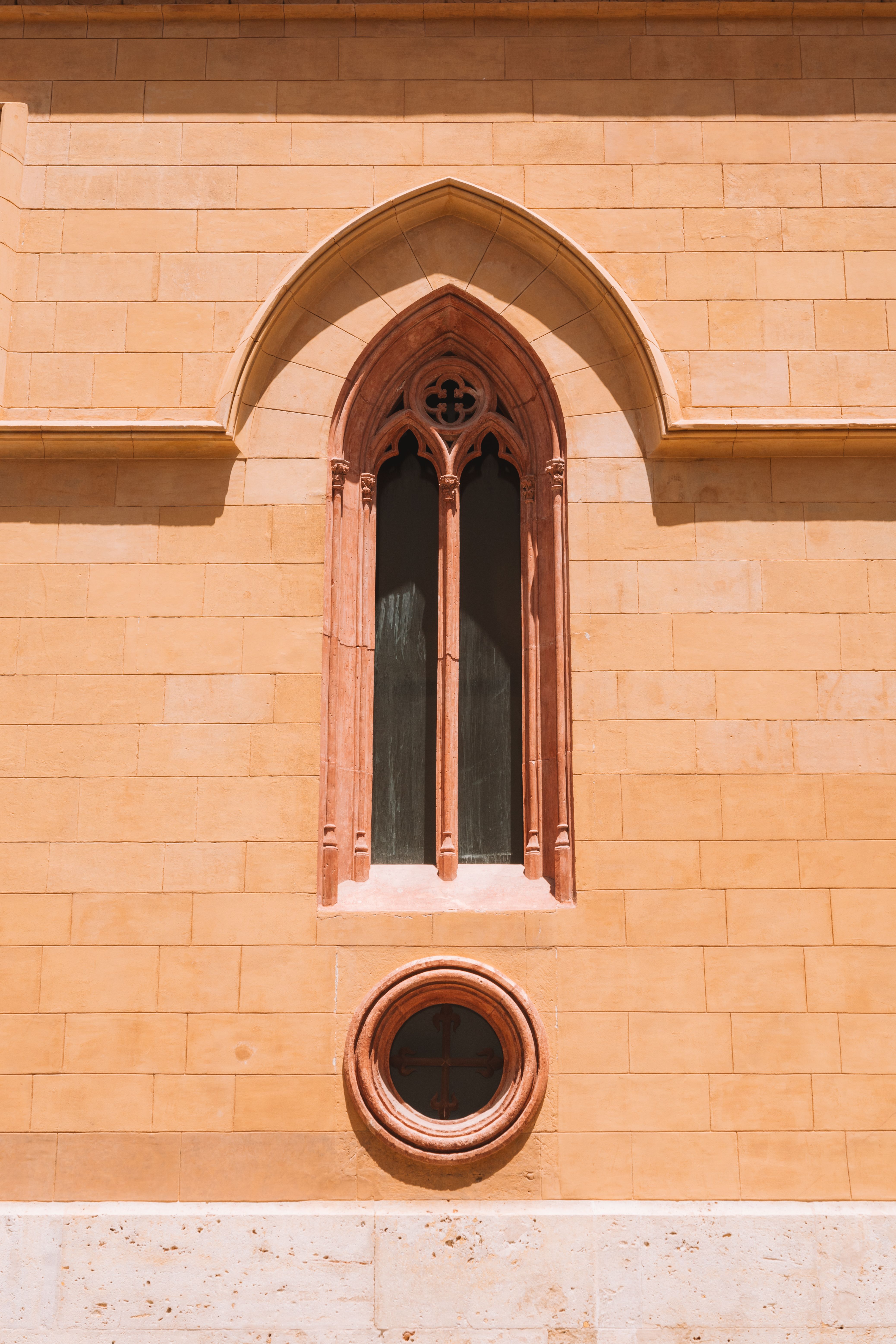 Fotomural Toma vertical de una ventana gótica en la fachada de una iglesia en Valencia, España. Los detalles arquitectónicos brillan en la iluminación.