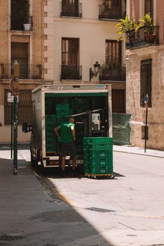 Busy street in Valencia, Spain with a delivery truck unloading crates.
