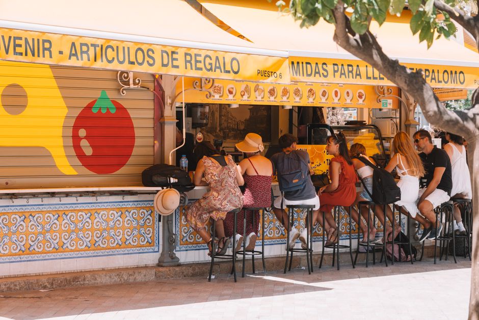 Personas disfrutando de una comida en un puesto de comida callejera en la soleada Valencia, España.