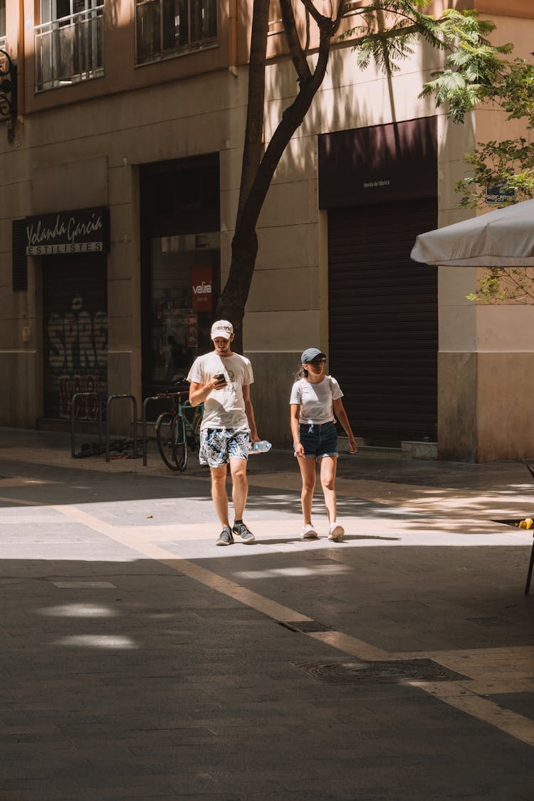 Man And Woman Walking On The Sidewalk In City In Summer 