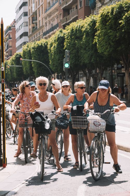 Free A group of women enjoying a leisurely bicycle ride down a sunlit urban street in Valencia, Spain. Stock Photo