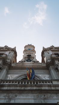 Low-angle view of Valencia City Hall facade featuring European Union and Valencian flags.