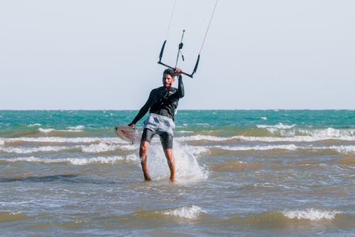 A Man Walking out of the Sea after Windsurfing 