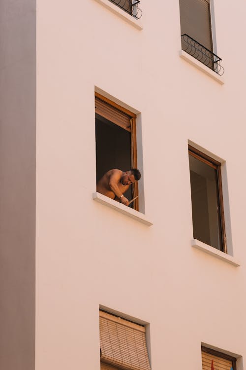 Man Standing in Building Window