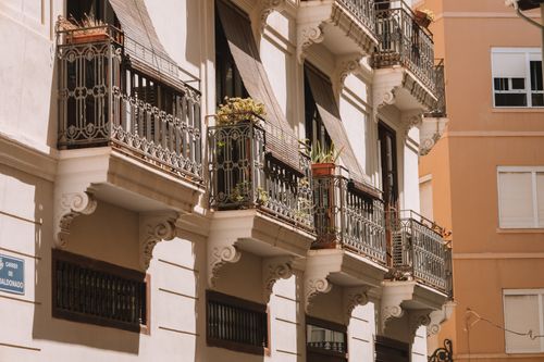Free Detailed view of sunlit balconies with ornate ironwork railings on an urban building facade. Stock Photo