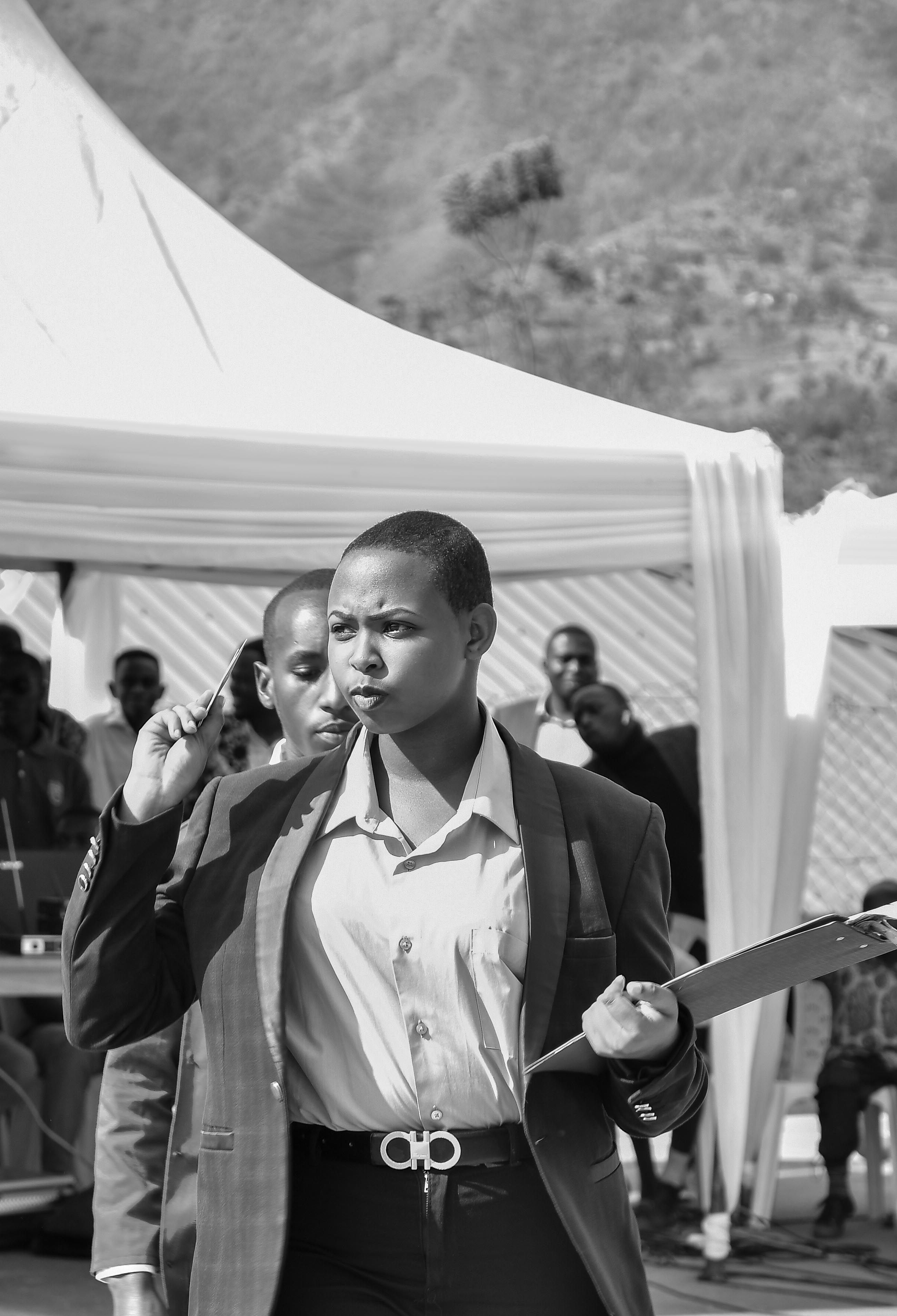 Confident woman holding a clipboard in an outdoor event setting, captured in black and white.