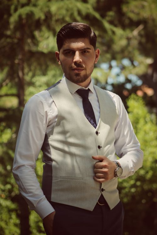 Free Young man in a vest and necktie posing elegantly outdoors, exuding confidence. Stock Photo