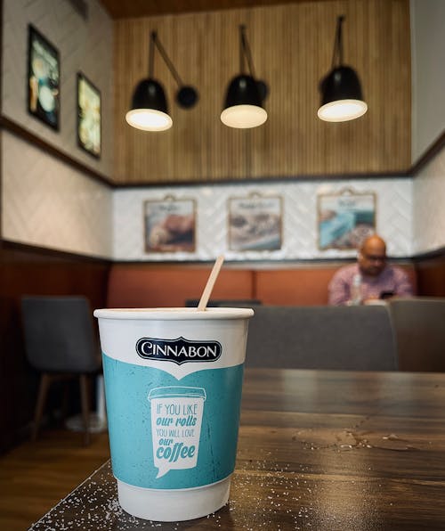 Coffee in Paper Cup on Table in Cafe