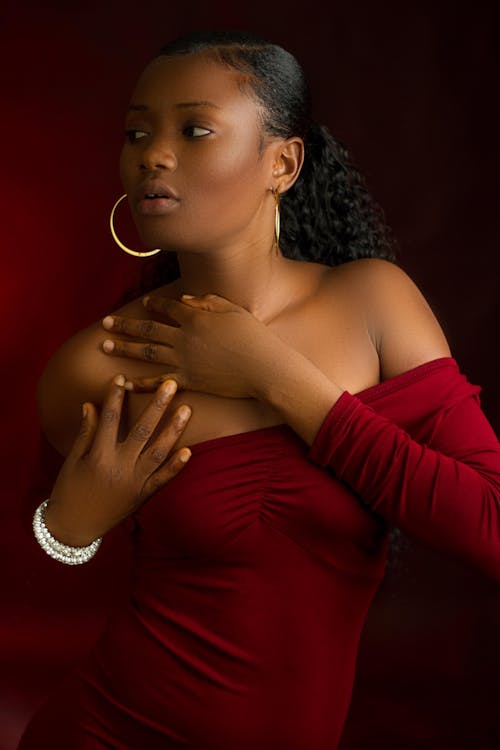 Standing Woman Wearing Red Off-shoulder Blouse Holding Her Chest