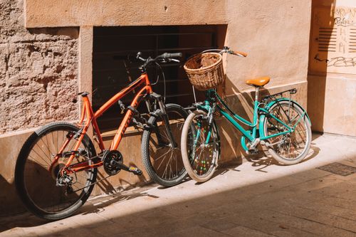 Free Two bicycles parked against a sunlit building wall in Valencia, Spain, capturing an urban European vibe. Stock Photo