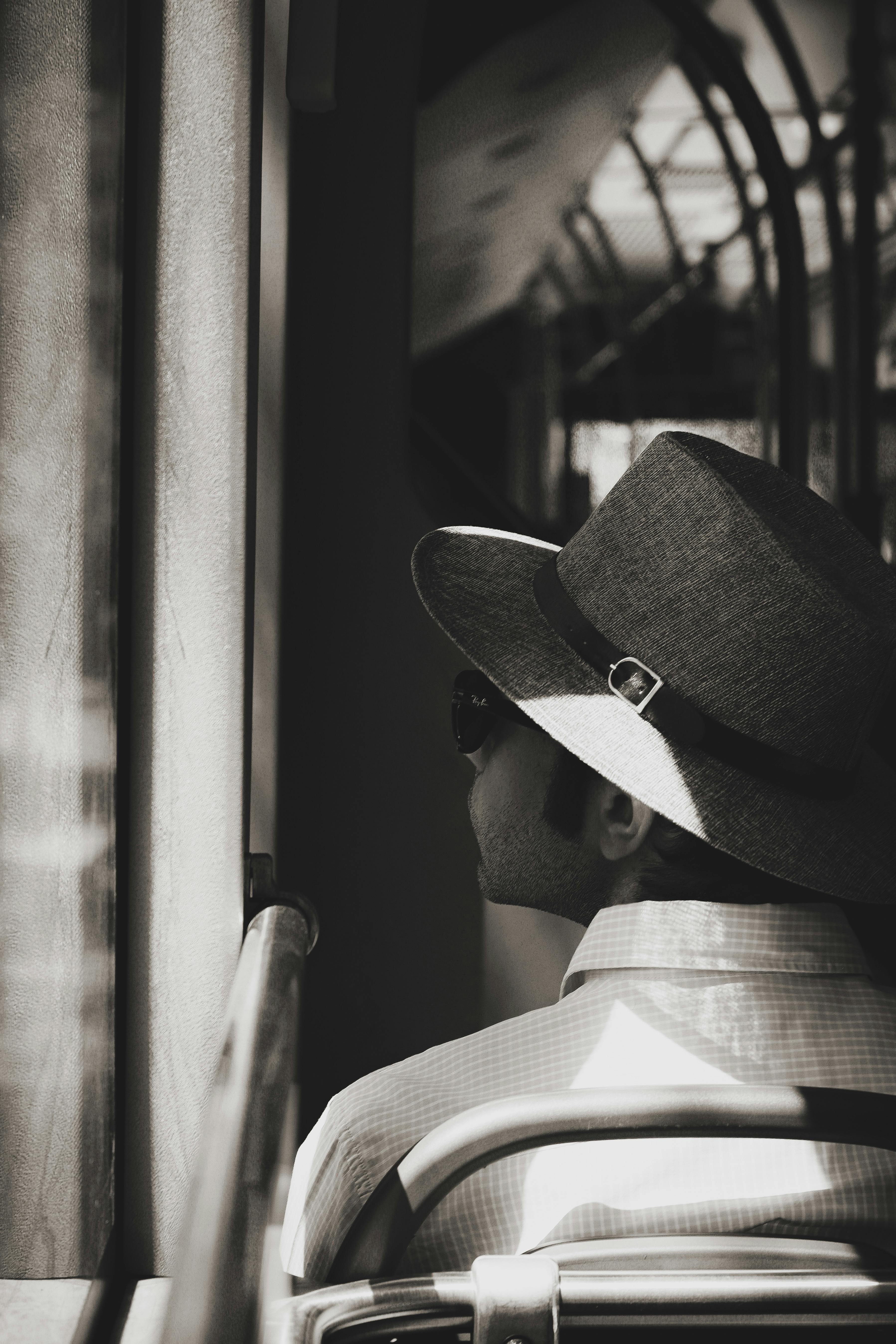 Free A contemplative man wearing a hat sits on a tram in Ankara, Türkiye, looking out the window. Stock Photo