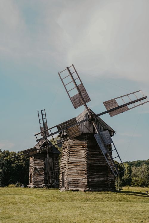 Free Charming rustic wooden windmills standing in a serene rural countryside setting against a clear blue sky. Stock Photo