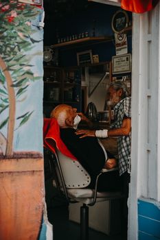 An elderly man getting a shave in a traditional barber shop in Ayvalık, Türkiye.