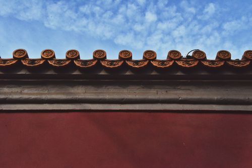 Free Close-up of a decorative roof with red tiles against a blue sky, reflecting traditional architecture. Stock Photo