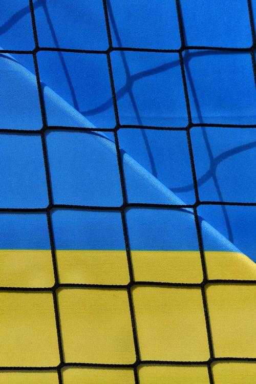 Free Close-up of the Ukrainian flag behind a sports net, creating an abstract pattern. Stock Photo