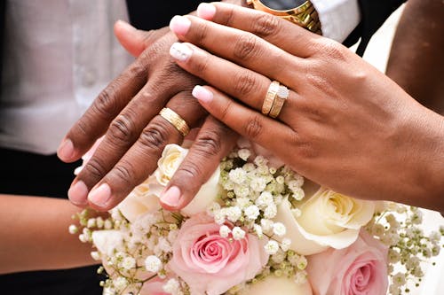 Hands of Man and Woman with Wedding Rings and a Bouquet of Flowers 